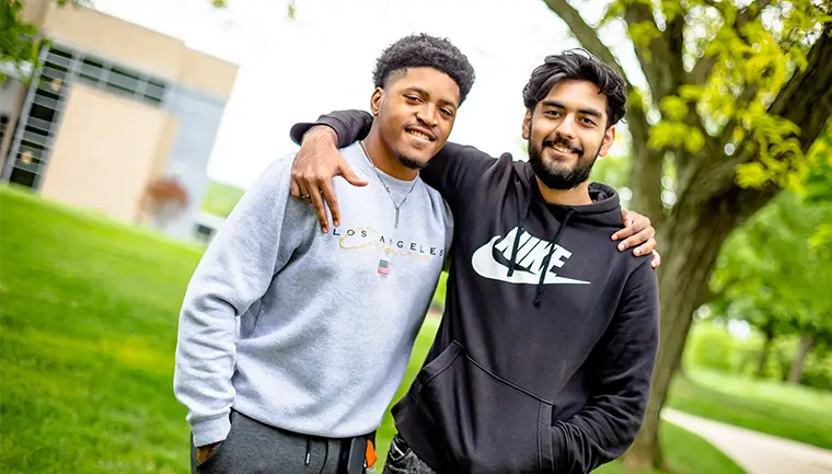 Two students standing outside on a sunny day