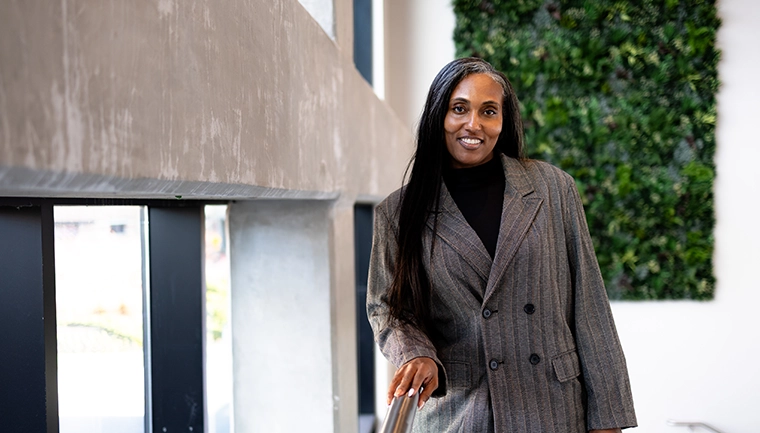 Student wearing scrubs sitting in lobby using laptop