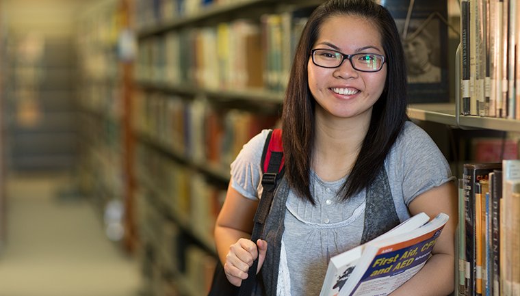 Student in library holding books