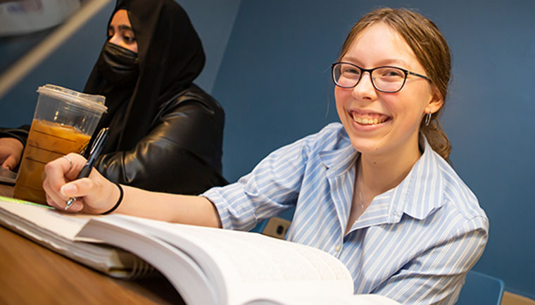 Photo of a student smiling while reading 