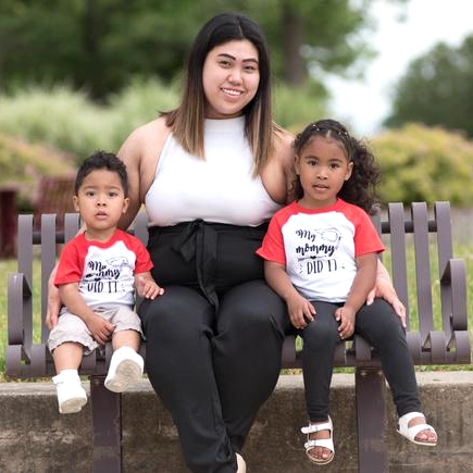 A mother sits between her two children on a park bench
