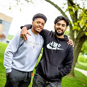 Two students standing outside on campus on a sunny day