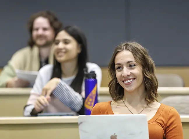 Three students are sitting together in a classroom