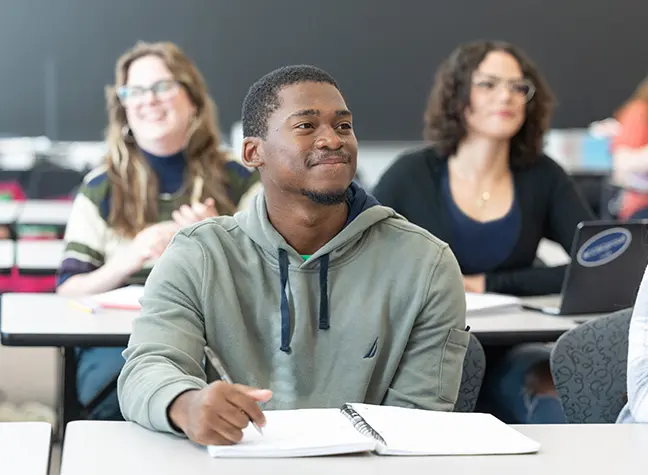Three students sitting in class listening to their instructor