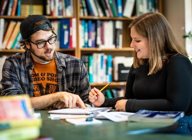 Two student look over notes together in the library