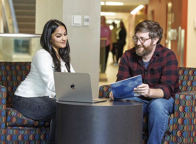 Two student sitting together reviewing a document