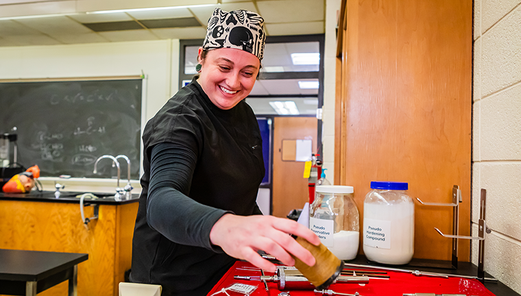 Mortuary Science faculty member standing by an assortment of urns