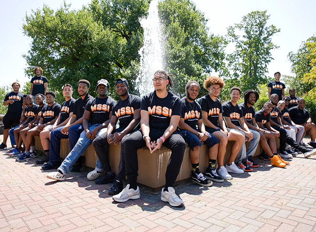 Male students sitting by a fountain