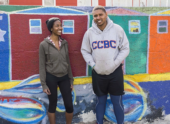 Volunteers stand in front of a colorfully painted wall.