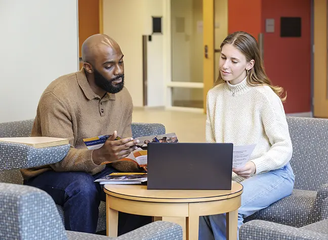 A tutor assists a student with work on her laptop.