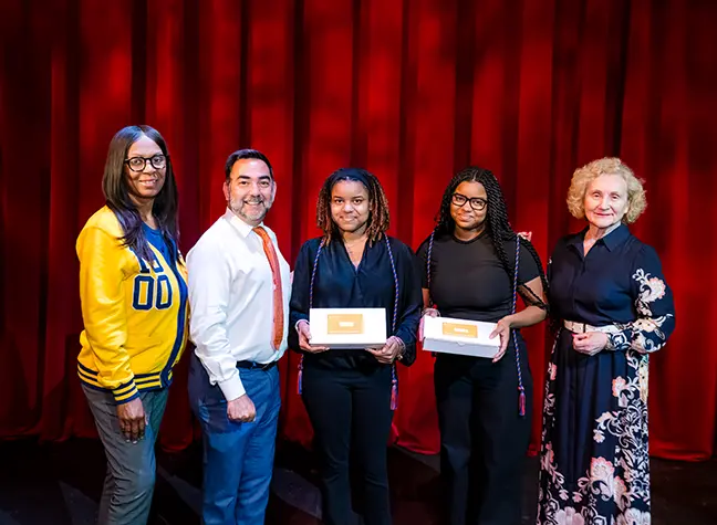 Two students in front of a backdrop that reads "Degrees to Succeed."