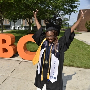 Kit Davenport holding up her hands and cheering in her 2025 Commencement regalia.