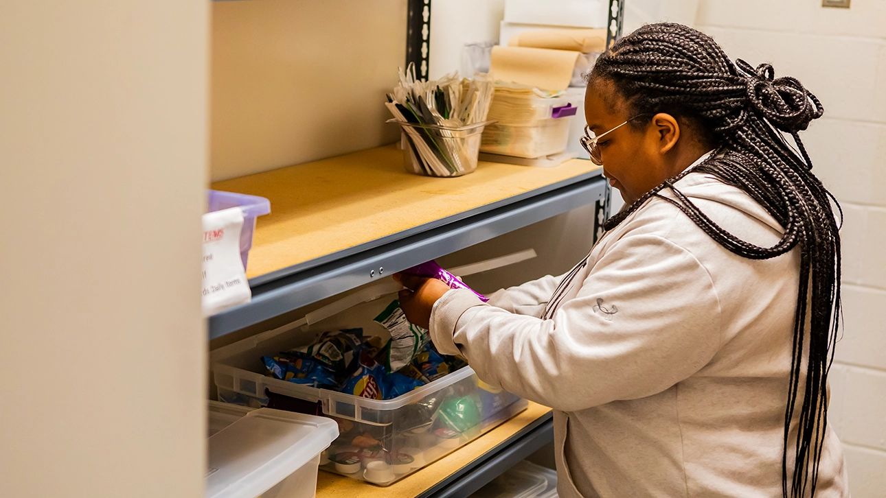 A Success Navigator pulls snacks out of CCBC's food pantry.
